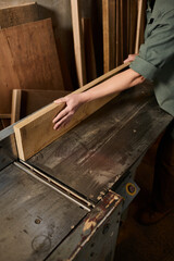 A dedicated carpenter works meticulously with a wooden plank in a bustling workshop, showcasing...