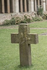 Stone cross standing in green grass near cloister wall