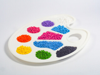 Assorted color masterbatch granules in pallete isolated on white background, polymer carrier of color pigments in plastics industry