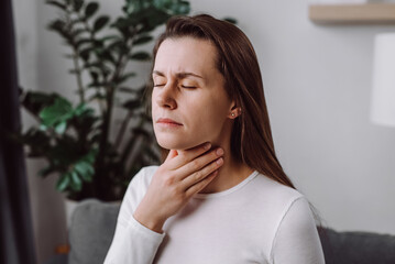 Close up of inflaming young woman use hands check self touch at sore throat, pain thyroid gland on...