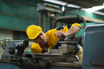 A man in a yellow safety helmet is working on a machine. Concept of caution and precision, as the...