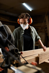 A focused female carpenter meticulously works with wood, showcasing her craftsmanship in a vibrant...