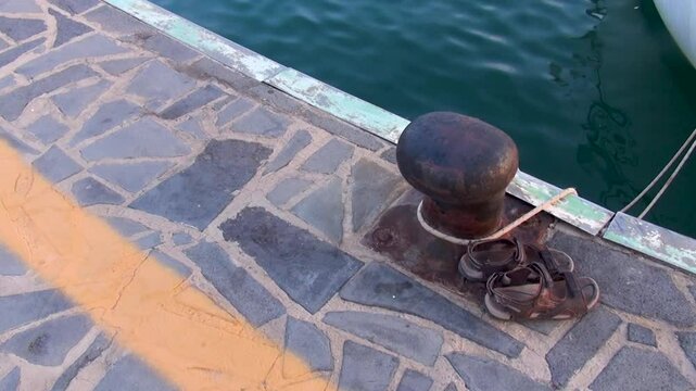 Details of a rusty bitt in the port where a boat is moored.