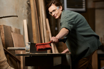 In a well-equipped workshop, a dedicated female carpenter skillfully crafts wood while focused on her project.