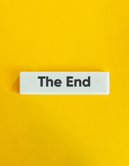 The End Word. Text on Block Letter Tile on Yellow Background. Minimal Aesthetic.