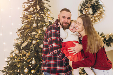 Happy family embracing near decorated christmas tree