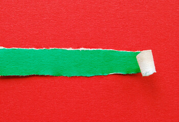 Torn off green paper strip with ripped borders on red paper background, Christmas concept for your text