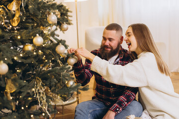 Bearded man and woman decorating christmas tree together