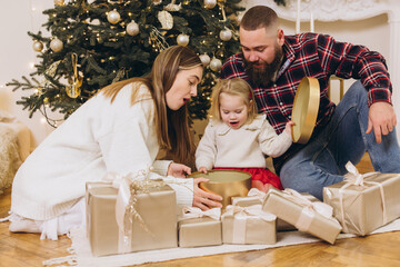 Family opening christmas gifts near decorated tree