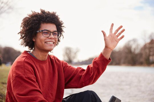 Gen Z boy outside hanging around beside a river and smiling at the camera. Munich, Germany