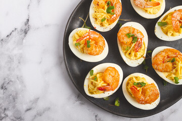 Boiled eggs stuffed with yolk and seasoned with mayonnaise, stuffed eggs with shrimp, on a black plate, selective focus, close-up, no people,