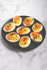 Boiled eggs stuffed with yolk and seasoned with mayonnaise, stuffed eggs with shrimp, on a black plate, selective focus, close-up, no people,