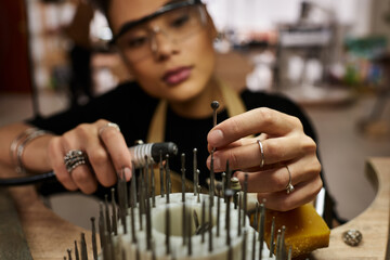 A talented woman carefully crafts stunning jewelry while focused on her precision work with tools.