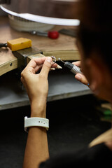 A talented woman focuses intently on creating beautiful jewelry with intricate details.