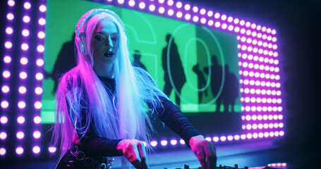 Portrait of Female DJ with Long Blonde Hair Performing Live at a Night Club, Playing Techno Dance...