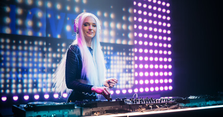 Portrait of a Beautiful DJ Making a Show on a Vibrant Stage, Entertaining a Large Audience in a...
