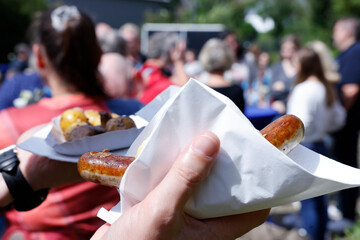 Mann hält Bratwurst in der Hand auf einem Volksfest