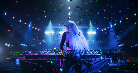 Female DJ Delivers a Live Performance of Electronic Music while Standing Behind Turntable Decks at a Massive Concert. Dance Beats Play at an EDM Concert with Falling Confetti. Footage from the Back