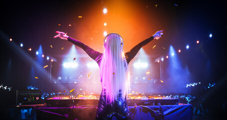 Caucasian Girl Performing at a DJ Concert Live on Stage. Talented Music Producer Dancing, Mixing Energetic Dance Hits on Turntables. Young Female Engaging with the Crowd. Back View