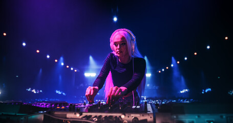 Young Beautiful Female DJ Playing Dance Music Sets, EDM, Techno, House Tracks at a Nightclub with Devoted Music Fans. Neon Lights and Excited Crowd Create a Party Atmosphere at a Festival