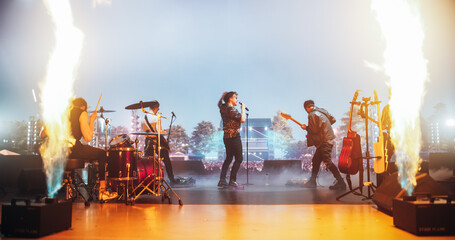 Energetic Rock Band Performing on Festival Stage with Fire Pyrotechnics Special Effects. Rock Music Artists Creating a Unique Show Experience With Dynamic Visuals and Powerful Alternative Music