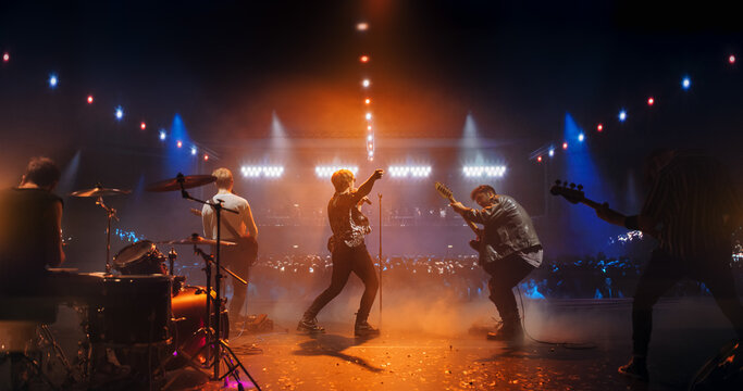 Stylish Lead Singer Performing at a Rock Concert Live on Stage. Talented Musicians Bringing Their Unique Sound, Playing Energetic Rock Hits. Young Band Engaging With the Crowd. Footage From the Back - Powered by Adobe