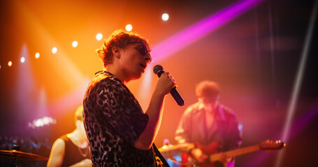 Male Lead Vocalist Delivers a Captivating Performance on Stage. Caucasian Rock Musician Singing Songs with Passion and Energy Under Colorful Lights. Indie Artist Performing at a Sold-Out Concert