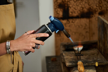 An artisan focuses intently while using a torch to shape exquisite jewelry in her studio.