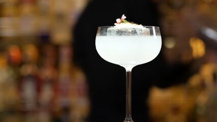 Closeup hand bartender using strainer in vodka coconut smooth fizzy cocktail at luxurious counter...