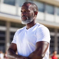 Fototapeta premium A medium close-up of a grey-haired Black man in white t-shirt. The shallow focus blurs the background.