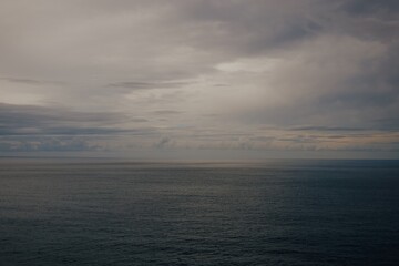 Raining sunset sky over the Atlantic Ocean, Tenerife. Minimalism. Misty dusk in the sea. Dramatic view. Tranquil empty landscape with soft golden gray sky. Natural gloomy weather.