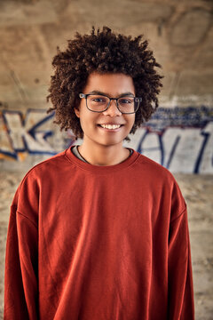 Gen Z boy outside under a bridge smiling at the camera. Munich, Germany
