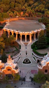vertical video: Park Guell aerial shot at sunrise, tourist landmark in Barcelona. Antonio Gaudi architecture. Dawn in Barcelona park Guell, Spain