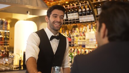 Focusing on smiling smart bartender preparing drinks at luxurious bar while engaging lively conversation with VIP customer at vibrant warm lighting atmosphere bottle bar and pub background. Vinosity.