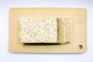 Some slices of raw tempeh on a white background. Tempeh is a nutrient- and protein-rich food with affordable retail prices in traditional markets.