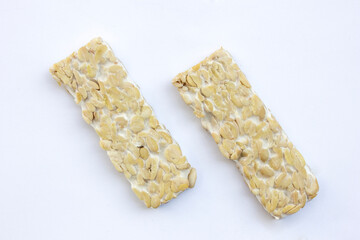 Some slices of raw tempeh on a white background. Tempeh is a nutrient- and protein-rich food with affordable retail prices in traditional markets.