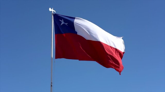 Chilean flag waving gracefully in the wind against a vibrant blue sky, symbolizing national pride and identity