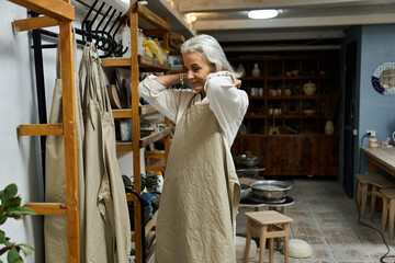 A mature woman delights in getting ready in her inspiring artistic workshop.