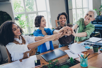 Photo of four diverse women businessladies feminists community give high five comfortable modern office room interior indoors workspace