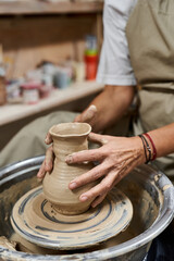 A talented woman expertly molds wet clay on a potters wheel, showcasing her craftsmanship.