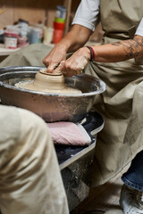 An artisan crafts a clay vessel on a pottery wheel in a cozy studio.