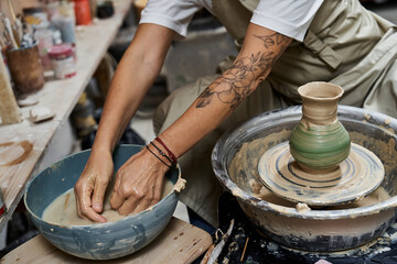 Hands of an experienced woman skillfully mold clay on a pottery wheel in a bright studio.
