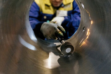 Worker cleans inner surface of pipe, selective focus, blurred face