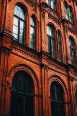 Obraz premium Vintage red-brick building facade with large windows showcasing detailed urban architecture in a bustling city