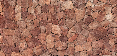 Rustic stone wall background, panoramic texture of rough reddish stones