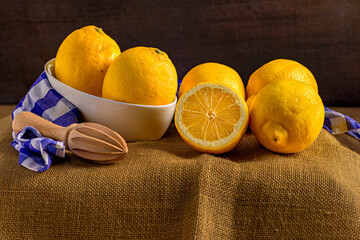 Fresh Lemons with Wooden Juicer on Rustic Fabric