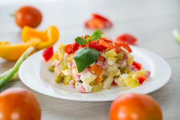 vegetable salad of boiled vegetables, with peas, sausage, sweet pepper. On a wooden table