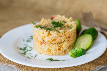 homemade cooked bulgur with Brussel sprouts in a plate, on a wooden table