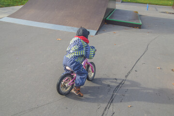 a child, a boy riding a running bike, a bicycle on a sports field, a photo without filters