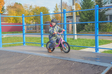 a child, a boy riding a running bike, a bicycle on a sports field, a photo without filters